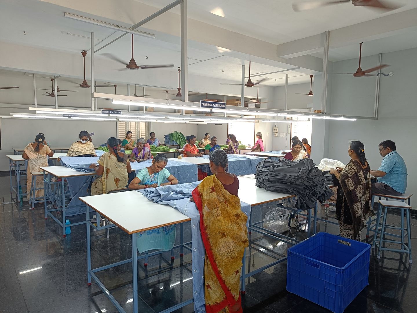 Inspection hall with staff checking finished textiles at long tables